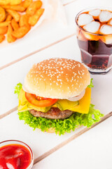 Juicy burger with potato, ketchup and beverage. Fastfood