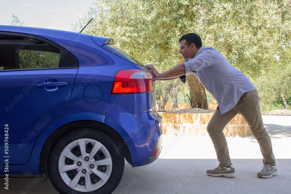 Wall mural photo of a man pushing his car after running out of gas. reference to the current expensive fuel