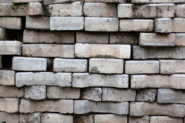 Textured background of a white brick wall. There is moss on the bricks in places.