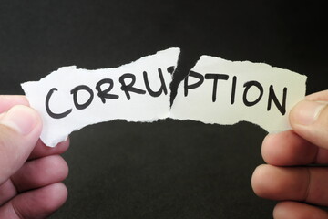 Stop and fight corruption concept. Human hand tearing a piece paper with written word corruption.