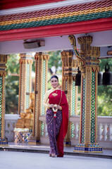 Portrait of young Asian women in traditional Thai costumes worshiping Buddha images with flower garlands. Preserving the good culture of Thai people during Songkran Festival, Thai New Year, April Fami