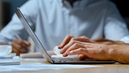 Office concept: young businessman typing on a computer keyboard against the backdrop of office work