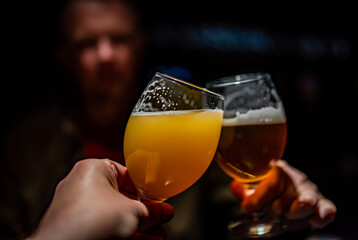 Two friends hands toasting with glasses of light beer at the pub or bar