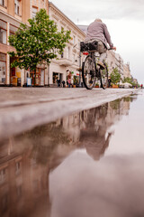 Deszcz i przejeżdżająca na rowerze osoba