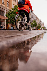 Deszcz i przejeżdżająca na rowerze osoba - obrazy, fototapety, plakaty