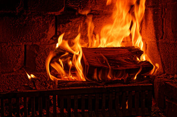 A large block of wood is burning nicely in an open fire grate