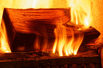 Warm orange and yellow flames flicker over wood in a fire place