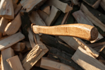An ax sticks out in a deck. A stacked pile of chopped firewood for the stove. Agriculture