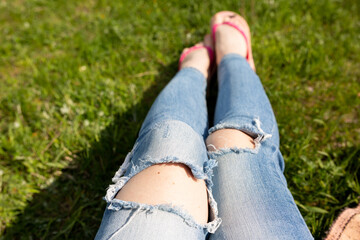 girls feet on grass in jeans. pedicure pink. women's legs. relax on the lawn. green grass