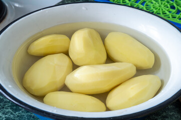 raw peeled potatoes in a bowl of water