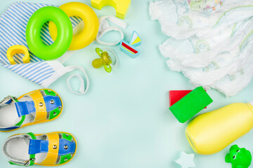 Children's background. Toys for kids, yellow sandals, pacifier, baby diapers, powder, cap on a blue background. Space for the text.