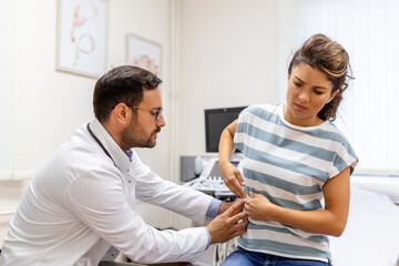 Patient telling physician about her pain and health problems during visit to hospital. Young woman...