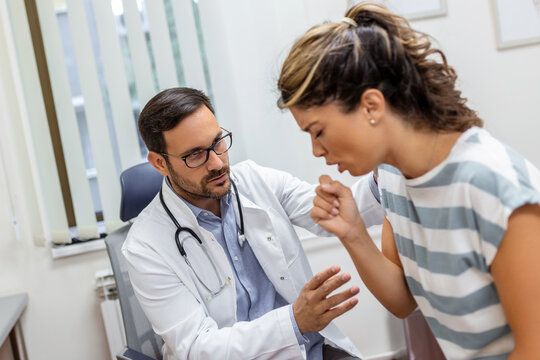 Coughing Woman Visiting Doctor At Clinic, Patient Coughing At Medical Appointment With Her Doctor. Sick Woman Visiting Doctor At The Hospital.