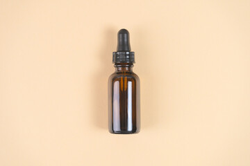 Amber glass bottle on beige background. Natural cosmetics packaging design. Flat lay, top view.