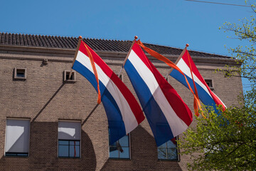 three times a Dutch flag in red white blue with an orange ribbon