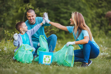 Mother and father teach their son to recycle plastic in recycling containers. They volunteer in a public park, clean up trash. - Powered by Adobe