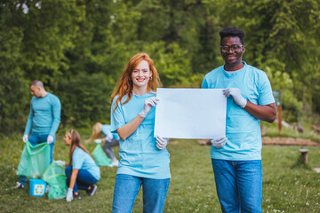 Two young people with blank paper in nature want to awaken people's consciousness. A group of...