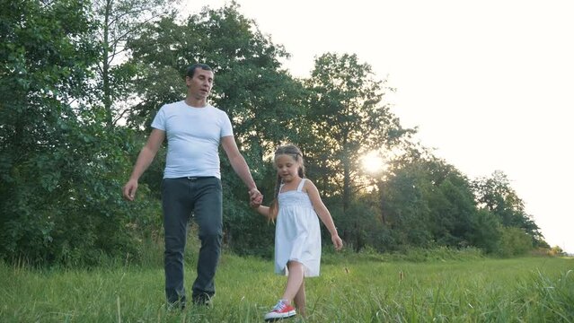 happy family. dad with little girl are walking in park fresh air in sun.family, paternity, child adoption concept. happy father, little girl are walking in summer park. family is resting in fresh air.