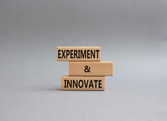 Experiment and innovate symbol. Concept words Experiment and innovate on wooden blocks. Beautiful grey background. Business and Experiment and innovate concept. Copy space.