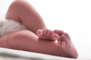 Sweet small feet of newborn baby on light blurred background.
