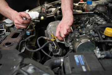 Fototapeta na wymiar Close up of car mechanic hands doing car service and maintenance. Mechanics workshop.