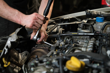 Fototapeta Close up of car mechanic hands doing car service and maintenance. Mechanics workshop. obraz
