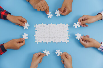 Group of business people assemble jigsaw puzzles on blue background,  teamwork, help and support in...