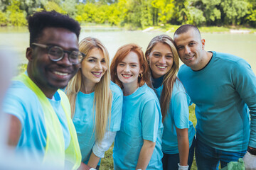 Young African man takes a selfie with a group of friends who are participating in a community...