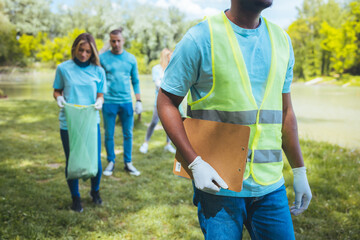 Happy volunteers connect after cleaning up the environment in a public park, walk one after the other and go to another location. Selective focus