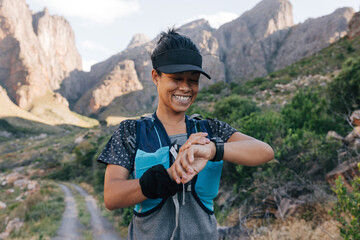 Fototapeta na wymiar Smiling female taking a break during hike looking at smart watch