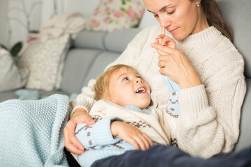 Mother and child, blond boy, lying on the couch at home