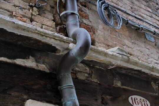 Goutti&egrave;re courb&eacute;e ancienne sur fa&ccedil;ade.