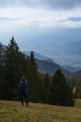 Fototapeta na wymiar A hiker takes pictures of the landscape of the Orobie Alps seen from the Val Seriana during an October day, near the town of Clusone, Italy - October 2021.