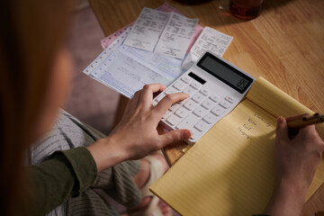 Woman calculating her monthly expenses and writing in notebook