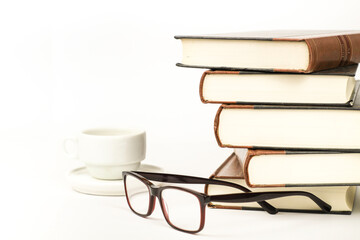 Stacked books next to cup of coffee and eyeglasses