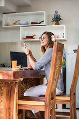 Young adult woman using smartphone and laptop, working from home concept.