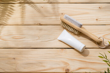 Foot brush and foot cream on wooden background