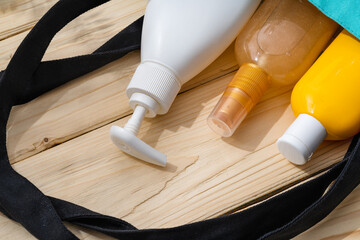 Sunscreen cream bottles in beach bag on wooden background