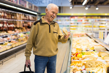 elderly man choosing cheese in supermarket