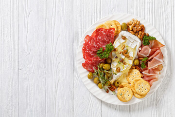 savory baked brie with crackers, salami, nuts, ham