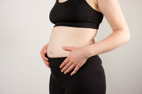 A woman shows an inflated thick belly, the concept of excess weight and weight loss.