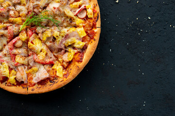 Margherita pizza on black stone background, top view. Margarita pizza with pineapple, and mozzarella cheese close-up.