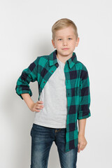 Portrait of cute stylish blond boy kid 7 years old in checked shirt and jeans