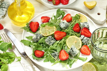 Salad with arugula, blue cheese and strawberries with white wine on a white background