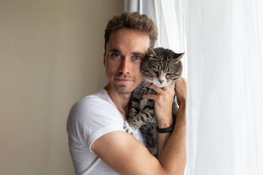 young man holds in his arms a cat