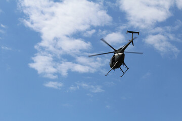 Fototapeta na wymiar Helicopter in flight with clouds and blue sky