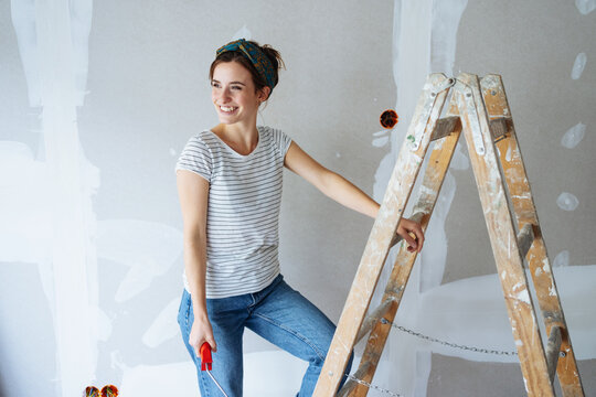 Young woman renovates her apartment and looks to the side