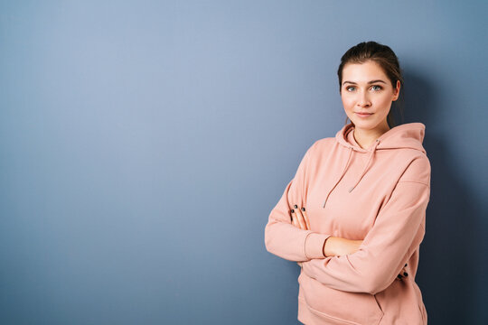 Woman standing with folded arms in front of blue background with copy space