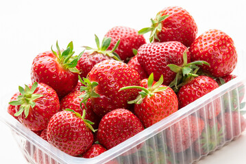 Ripe strawberries in a plastic box. Isolate on white background