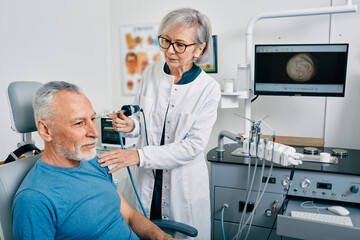 Ear endoscopy. ENT doctor examining mature man's ear using endoscope at otolaryngology clinic